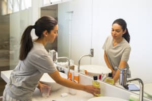 Person at the bathroom sink reaching for rinse to pour into an empty cup.