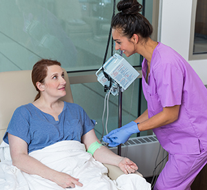 Health care provider caring for woman having infusion treatment.