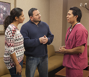 Healthcare provider talking to man and woman in hospital waiting room.