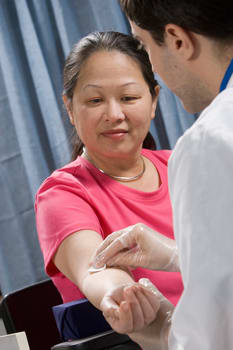 Health care provider preparing to draw blood from person's arm.