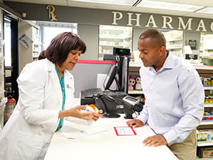 Pharmacist talking to person at pharmacy counter.