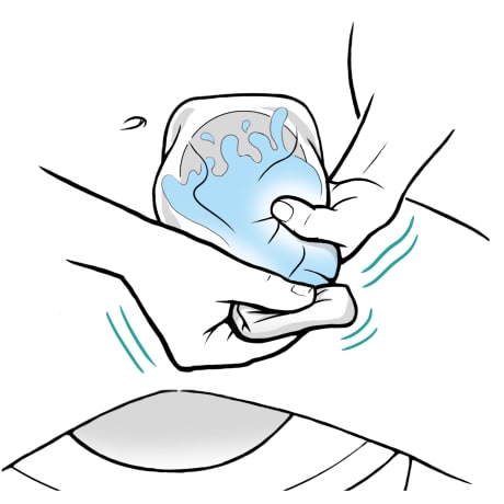 Person folding end of ostomy bag closed and shaking bag gently with water inside.