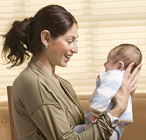 Woman holding baby upright in lap.