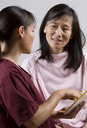 Healthcare provider talking to woman in exam room.