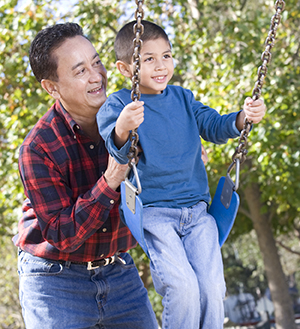 Man pushing boy on swing.