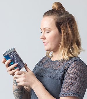 Woman reading nutrition label on can.