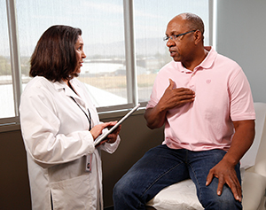 Health care provider talking to man in exam room.