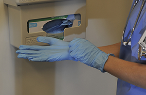 Closeup of healthcare provider putting on surgical gloves.